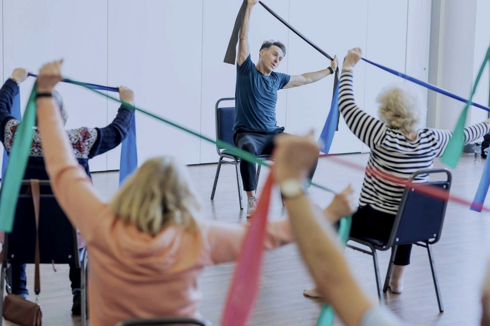 An instructor leading a group class with resistance bands while participants follow along.