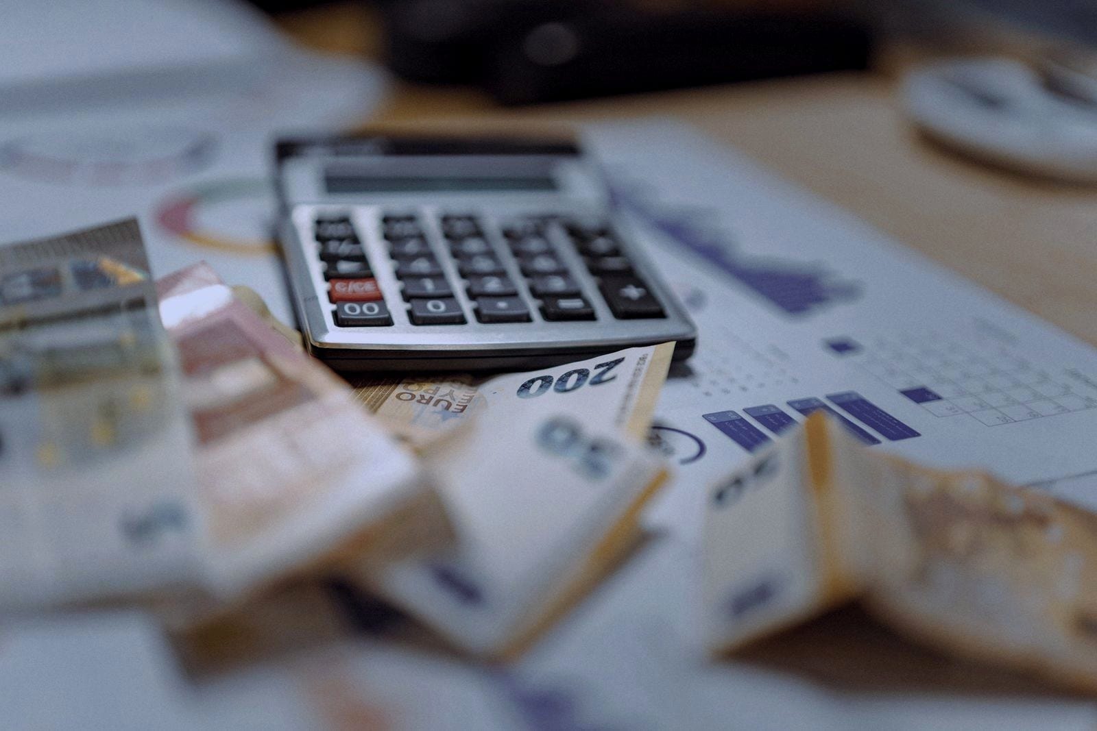 Calculator on top of euro banknotes and printed charts.