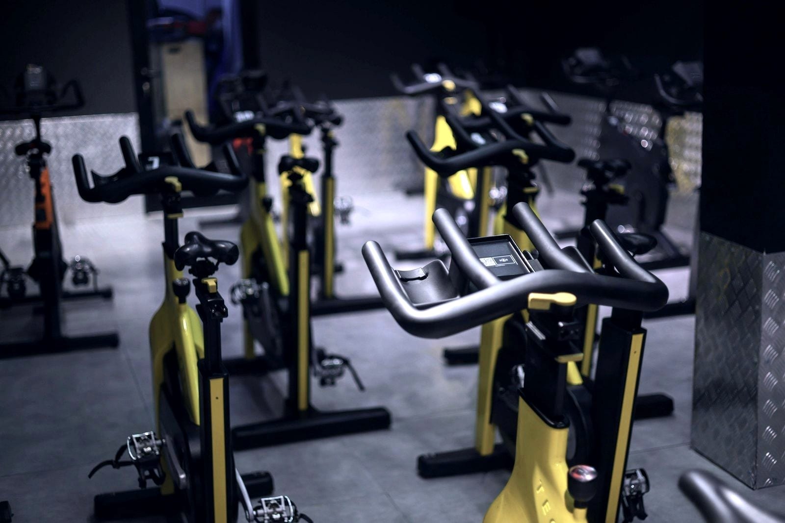 Fila de bicicletas de ciclismo indoor vazias numa sala de aulas.