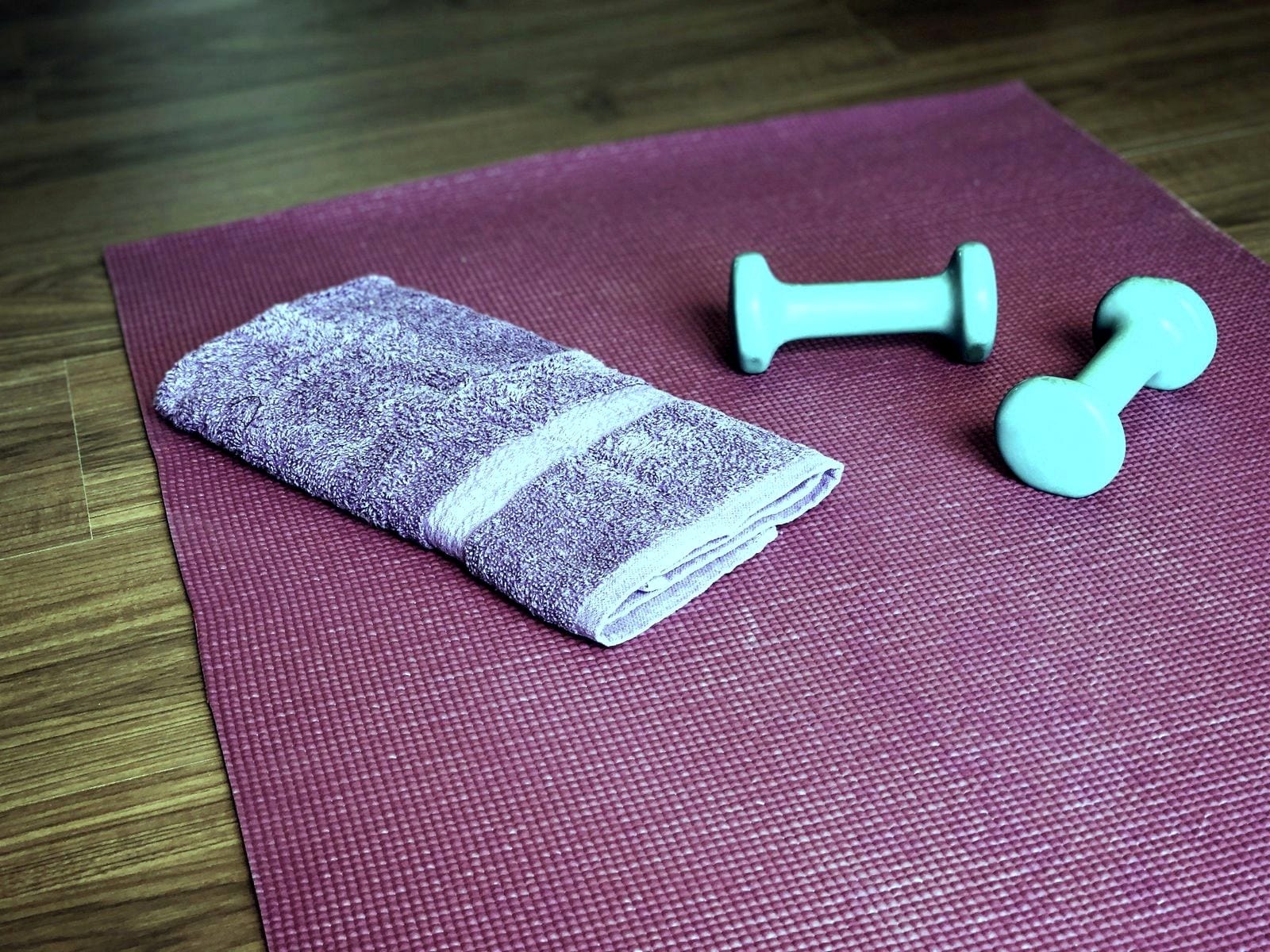 Exercise mat with a towel and two small dumbbells, set up for someone who has not arrived yet.